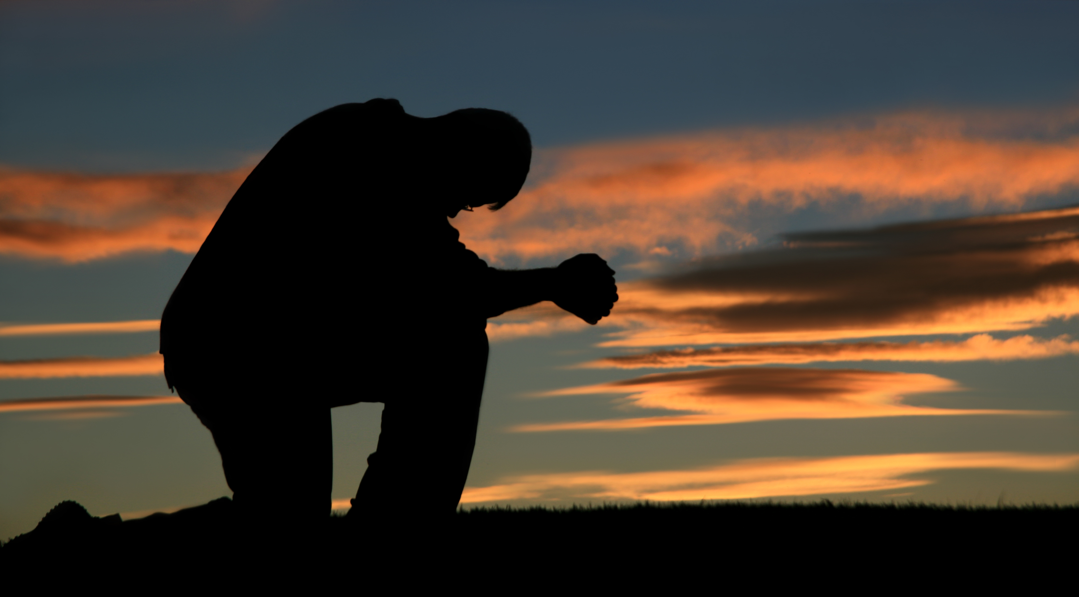Молящийся человек на фоне заката