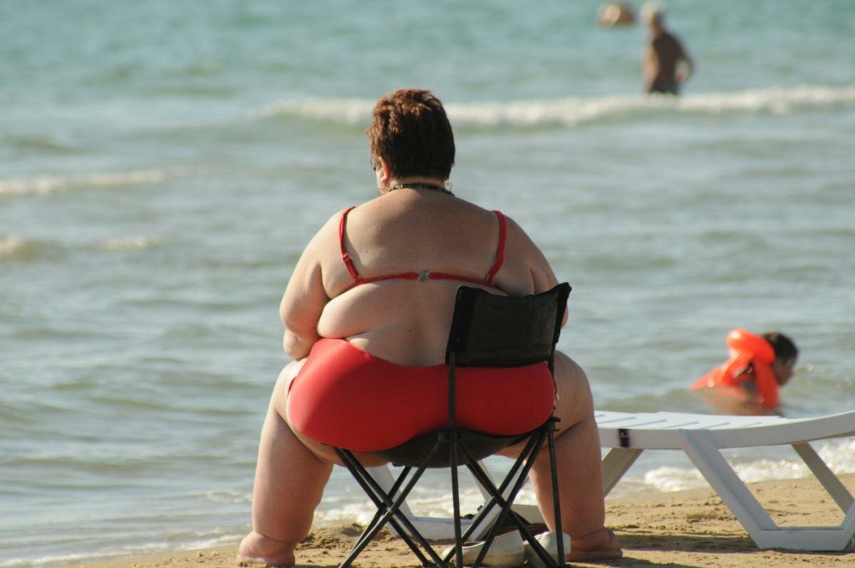 Мужик на пляже снимает на камеру жирную и большую жопу в купальнике