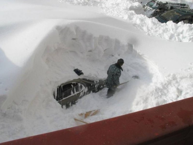 Откапывает машину из снега
