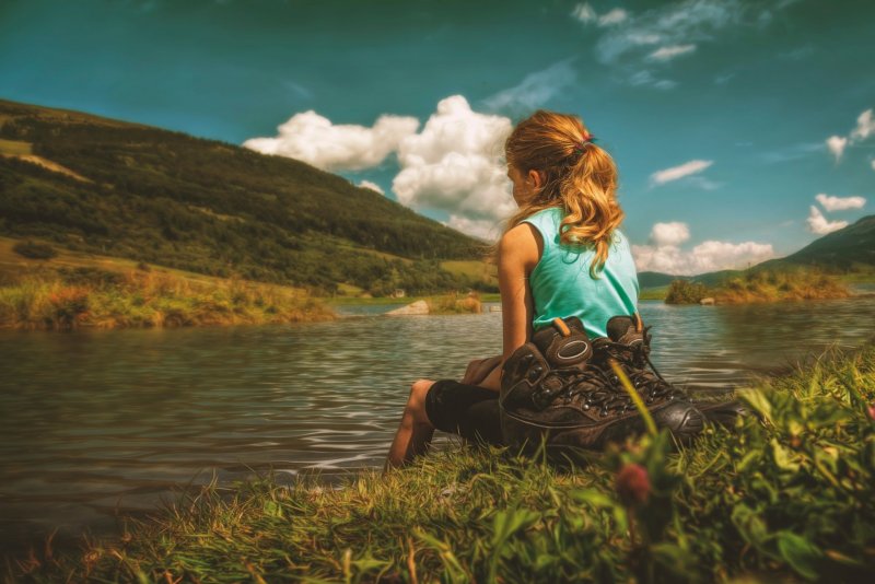Девушка сидит на берегу реки