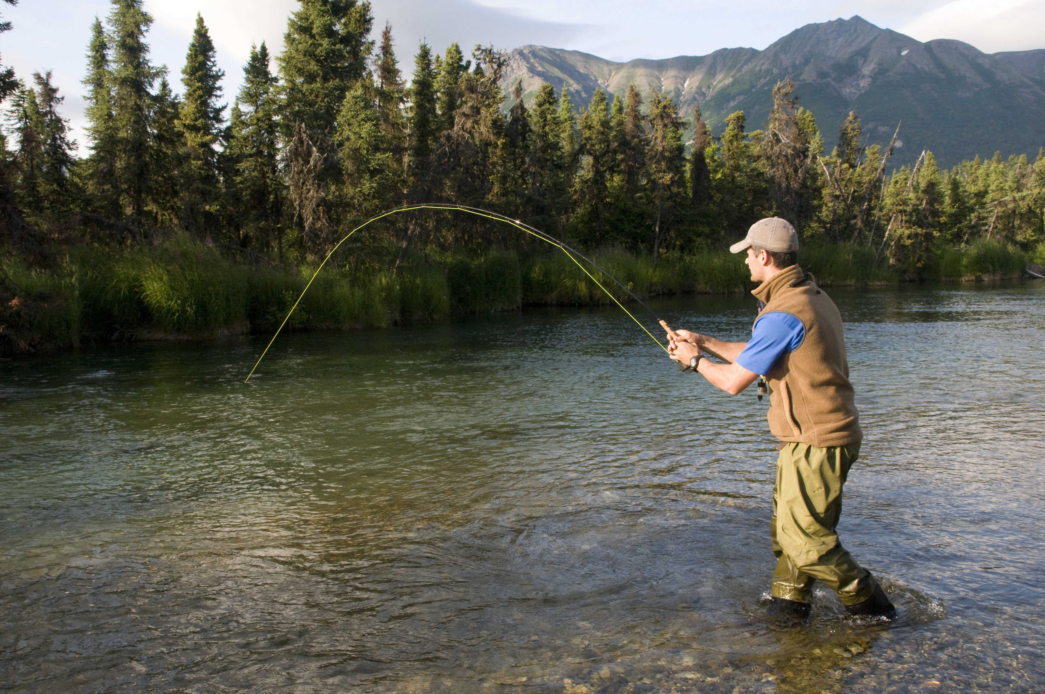 Мужик поймал рыбу. Человек рыбачит. Лето рыбалка. Рыбак с удочкой. Рыбалка на реке.