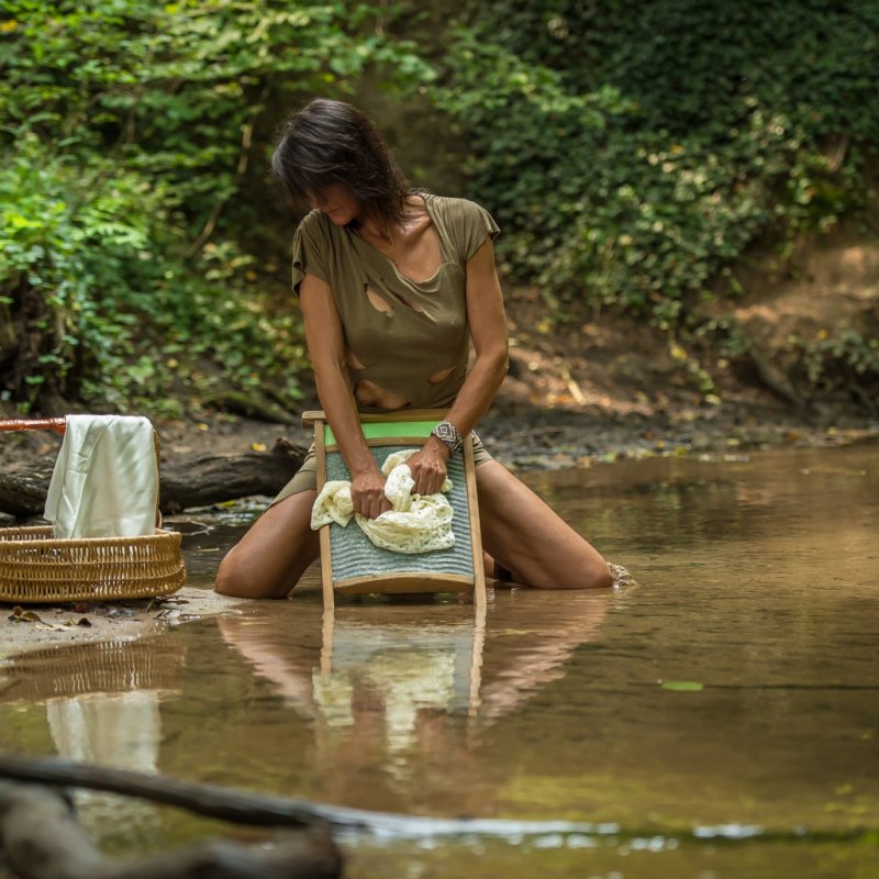Девушка стирает белье в реке