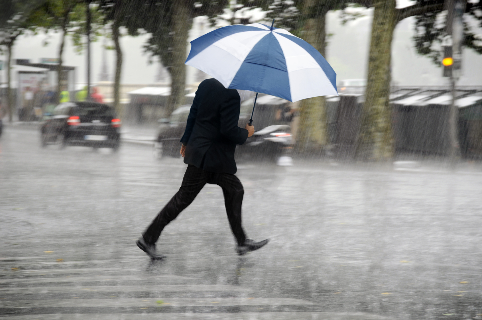 Человек с зонтом. Человек под дождем. Мужчина с зонтом под дождем. Сильный ливень.