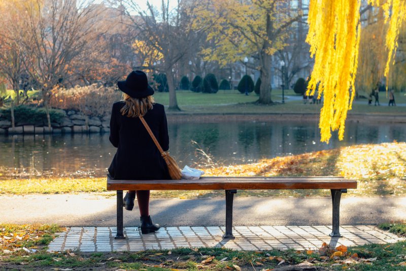 Женщина в парке на скамейке осенью